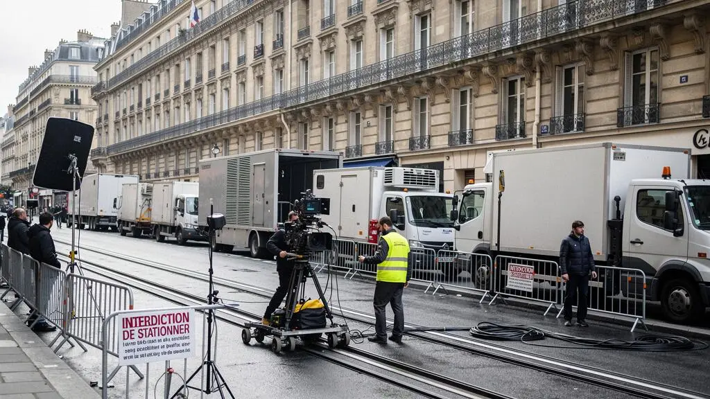 Équipe de tournage cinéma en action dans une rue parisienne avec véhicules techniques garés sur emplacements réservés par ventousage